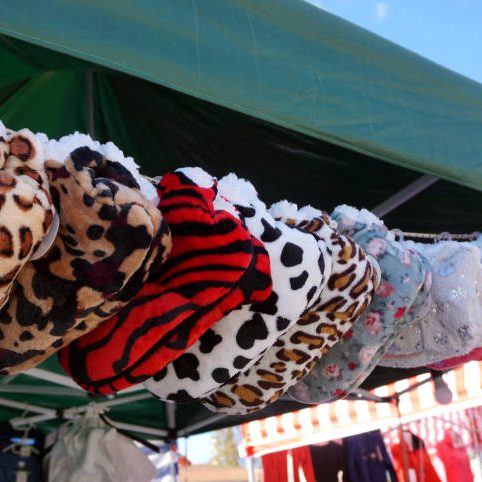 Colorful and warm winter slippers made from fake synthetic fur, lined on the rope and preparing to sell at the folk street festival